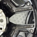 Close-up of a black camera body showing a textured metal plate with embossed numbers and a country marking readout.