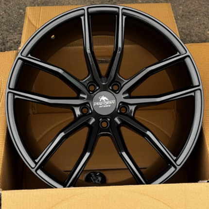 Black multi-spoke alloy car wheel in a cardboard box, ready for installation or shipment.