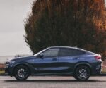 Dark blue crossover SUV parked on a road with a large autumn-colored tree in the background