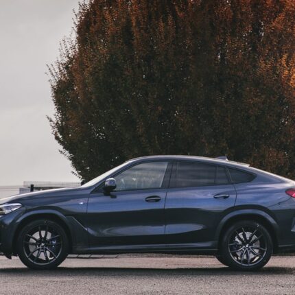 Dark blue crossover SUV parked on a road with a large autumn-colored tree in the background