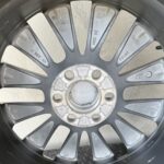 Close-up of a car alloy wheel with multiple gray spokes and a central hub, showing wear and dust on the surface.