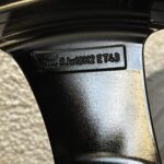 Close-up of a glossy black car wheel with a stamped rim label reading 5J×18H2 ET43.