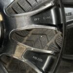 Close-up of a black alloy wheel with engraved text 'UPP' and 'K3.01' and a treaded tire in the background.