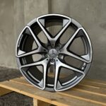 Close-up of a silver and black alloy wheel with a Mercedes logo, resting on wooden pallets outdoors.
