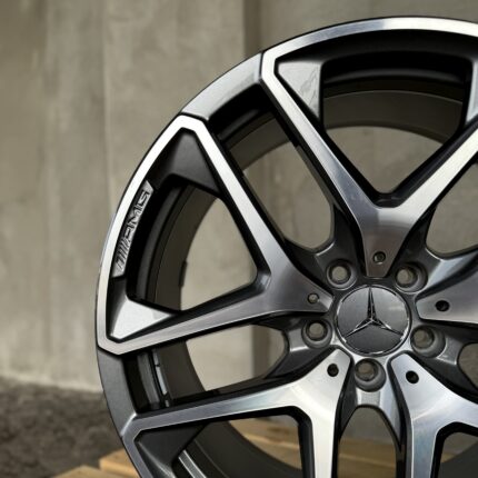 Close-up of a silver and black alloy car wheel rim with geometric spokes and openings.