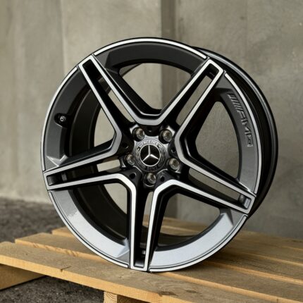 Close-up of a black Mercedes-Benz alloy wheel with silver detailing resting on a wooden pallet.