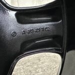 Close-up of a black textured metal surface with a glossy curved edge and embossed text/markings partially visible.