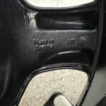 Close-up of a black textured surface with embossed text, curved metal edge, and a white rounded knob at the bottom right.