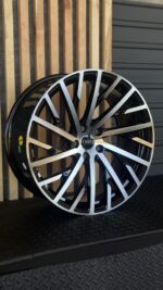 Close-up of a two-tone Audi alloy wheel with many split spokes and the Audi emblem at the center cap.