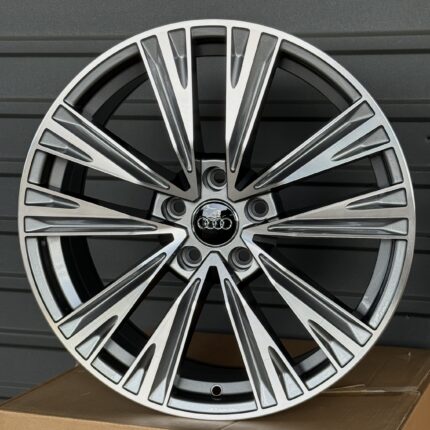 Close-up of a silver multi-spoke alloy car wheel resting on a cardboard box.