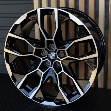 Close-up of a black and chrome BMW alloy wheel with angular spokes and the BMW emblem at the center as a focal point.