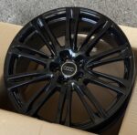 Black glossy Audi alloy wheel with a multi-spoke design and Audi center cap in a cardboard box.