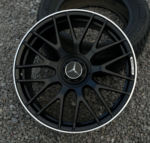 Close-up of a black multi-spoke AMG alloy wheel with a silver rim, featuring the Mercedes-Benz star emblem in the center and AMG badge on the rim edge.