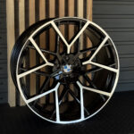 BMW alloy wheel with black and white split spokes and a central BMW roundel label on a display stand