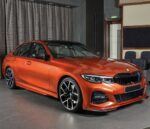 Red BMW sedan on showroom floor with glossy finish and large black alloy wheels in a modern showroom.