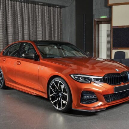 Red BMW sedan on showroom floor with glossy finish and large black alloy wheels in a modern showroom.