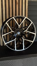 Black and white BMW alloy wheel rim with intricate spokes and center BMW emblem on a dark backdrop