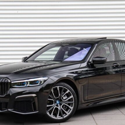 Black BMW sedan parked on a paved surface, showing the front grille and side profile against a striped wall.