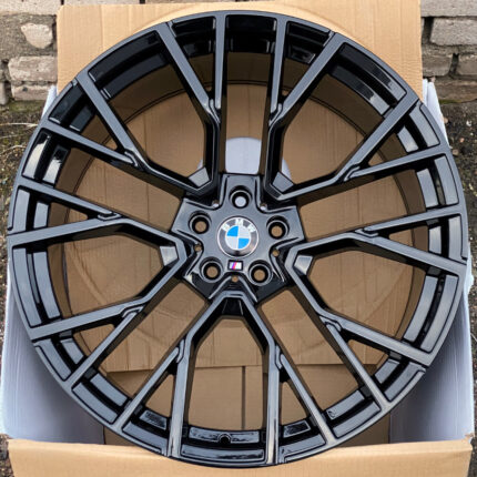 Black glossy BMW alloy wheel with a multi-spoke design and center BMW badge in a box.