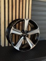 Close-up of a black and silver Audi alloy wheel leaning against wooden slats.
