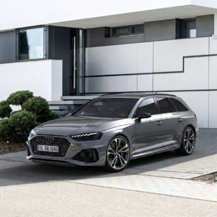 Gray Audi SUV parked in the driveway of a modern white-and-gray house with a paneled facade.