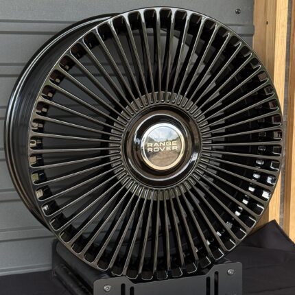 Close-up of a glossy black alloy wheel with chrome spokes and a Range Rover center cap.