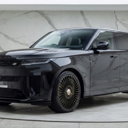 Grey Range Rover SUV on display in a marble-walled showroom, front three-quarter view with distinctive lattice wheels.