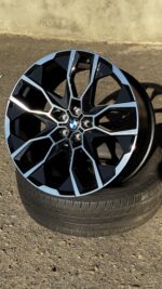 BMW alloy wheel with a geometric black-and-blue spoke pattern mounted on a tire, close view
