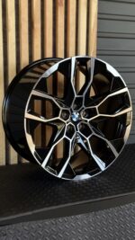BMW alloy wheel with black and silver angular spokes and a central blue-and-white BMW emblem