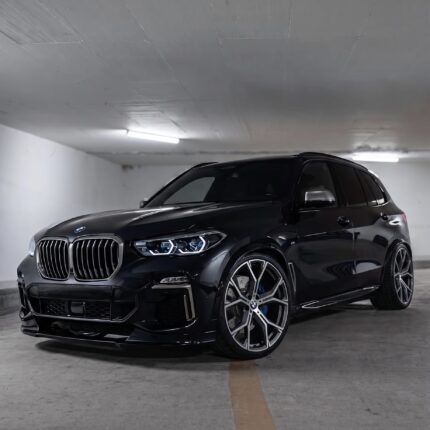 Front three-quarter view of a dark BMW SUV parked in an underground garage, showing large kidney grille and alloy wheels