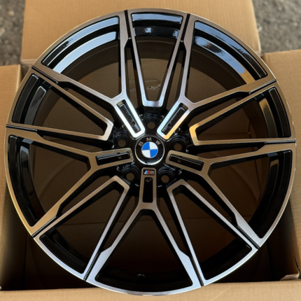 BMW alloy wheel with M badge, black and silver spokes in a cardboard box.