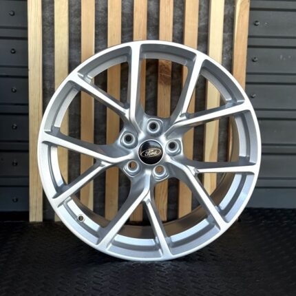 Silver alloy car wheel with ten split spokes and a Ford center cap (product shot)./ Silver 10-spoke Ford alloy wheel displayed against a backdrop.