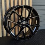 Glossy black multi-spoke Ford alloy wheel with a centered Ford emblem.