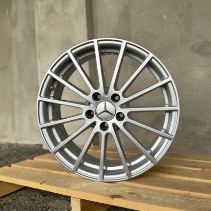 Silver Mercedes-Benz alloy wheel with multiple spokes, resting on a wooden pallet.