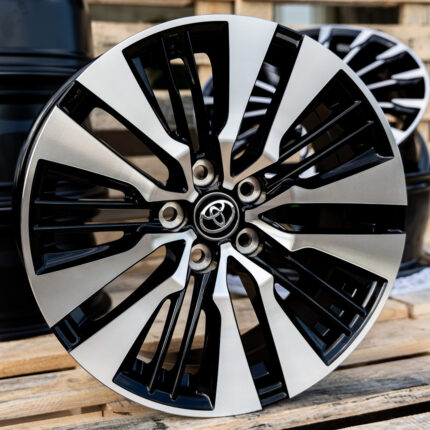 Close-up of a silver and black multi-spoke alloy wheel with Toyota center cap, resting on a wooden pallet