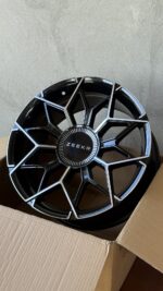 Black geometric car wheel rim in a cardboard box, center cap reads ZEEKR.