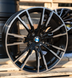Black and silver BMW alloy wheel with a multi-spoke design resting on wooden pallets