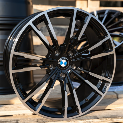 Black and silver BMW alloy wheel with a multi-spoke design resting on wooden pallets