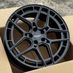 Black matte finish alloy wheel with a multi-spoke design, centered in a cardboard box; center cap reads 'Forza Wheels'.