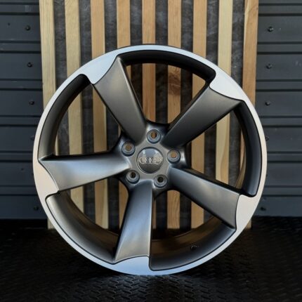 Audi five-spoke alloy wheel with silver and gunmetal finish and a central Audi emblem.