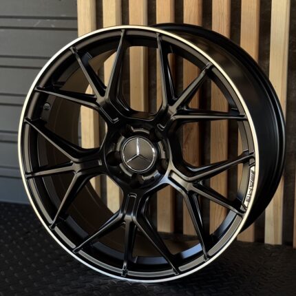 Black Mercedes alloy wheel with a silver Mercedes star center cap and AMG emblem on the rim edge.