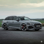 Grey Audi A6 Avant on a paved surface with green fields in the background, front-right three-quarter view.