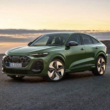Green Audi SUV parked on a paved surface at sunset, showing bold grille and large alloy wheels.