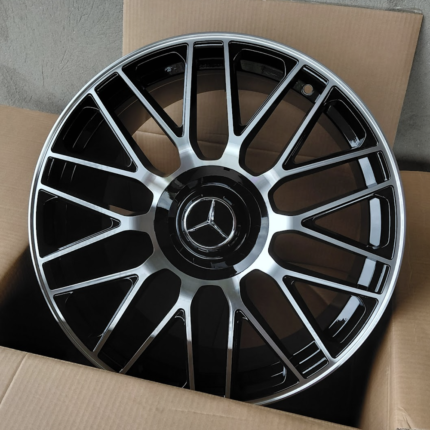 Shiny multi‑spoke alloy car wheel with a Mercedes emblem in the center, resting in a cardboard box.