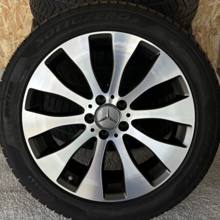 Close-up of a silver multi-spoke Mercedes wheel with a black tire and center cap featuring the Mercedes star logo