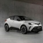 White Toyota C-HR Hybrid SUV parked in a gray concrete garage, showing its front-right profile.