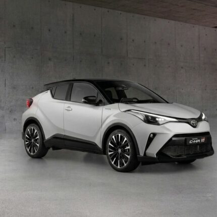 White Toyota C-HR Hybrid SUV parked in a gray concrete garage, showing its front-right profile.