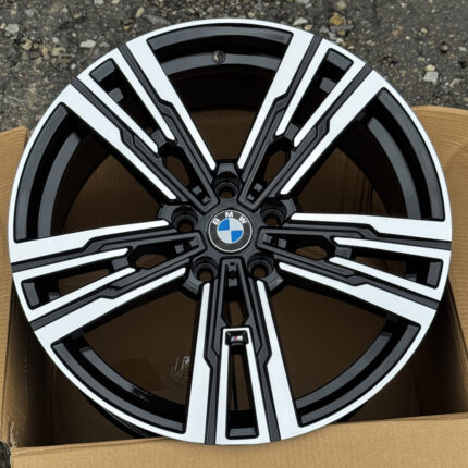 BMW alloy wheel with a black and silver multi-spoke design and the blue-and-white BMW center badge, inside a cardboard box