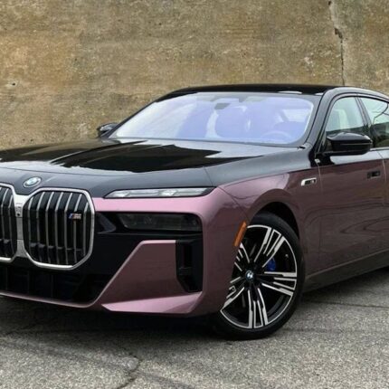 Front three-quarter view of a purple BMW luxury sedan with a bold chrome grille, parked on an asphalt lot.