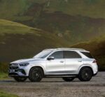 Silver Mercedes-Benz SUV parked on a gravel road with green hills in the background